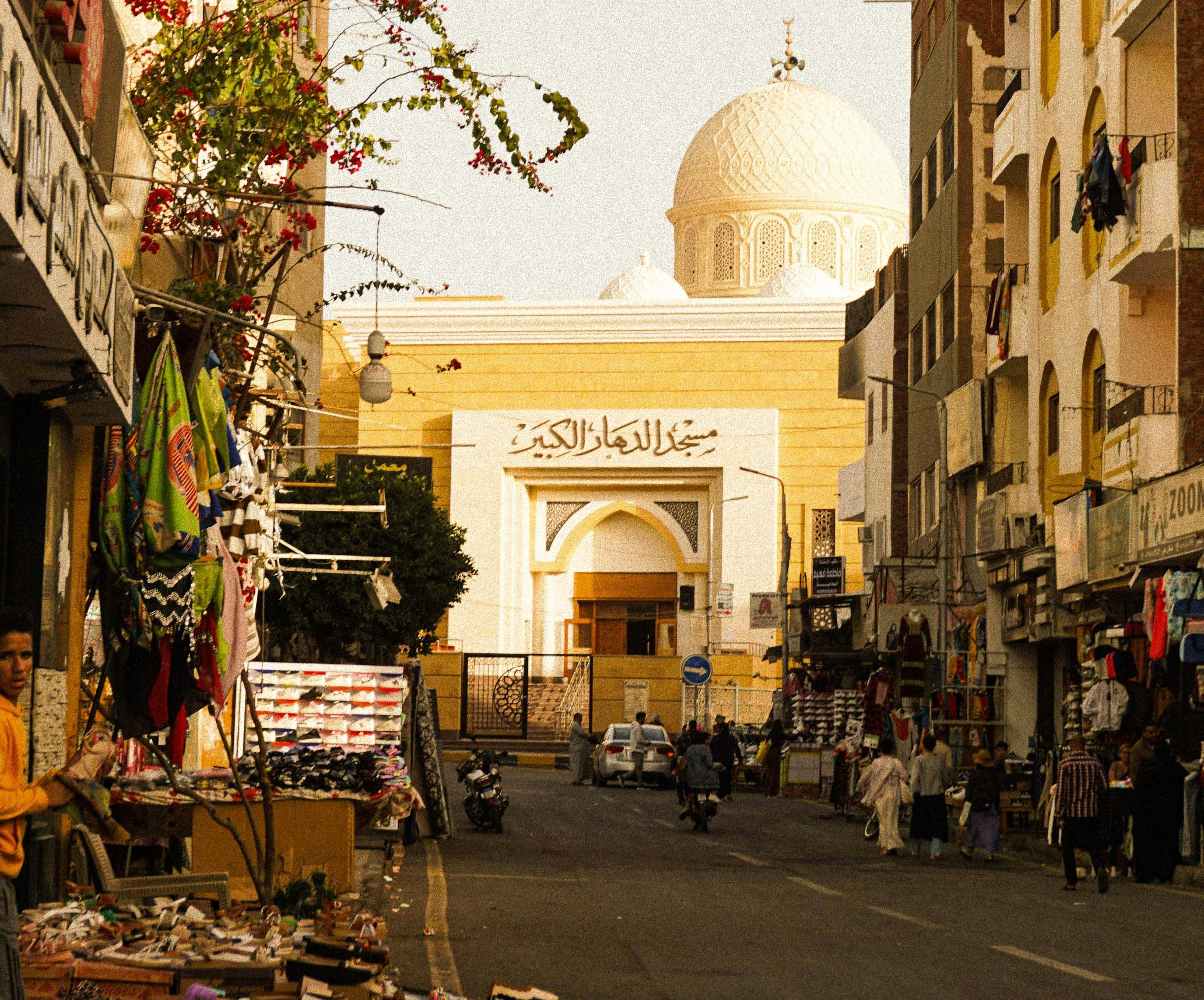 Rue commerçante menant vers une grande mosquée blanche