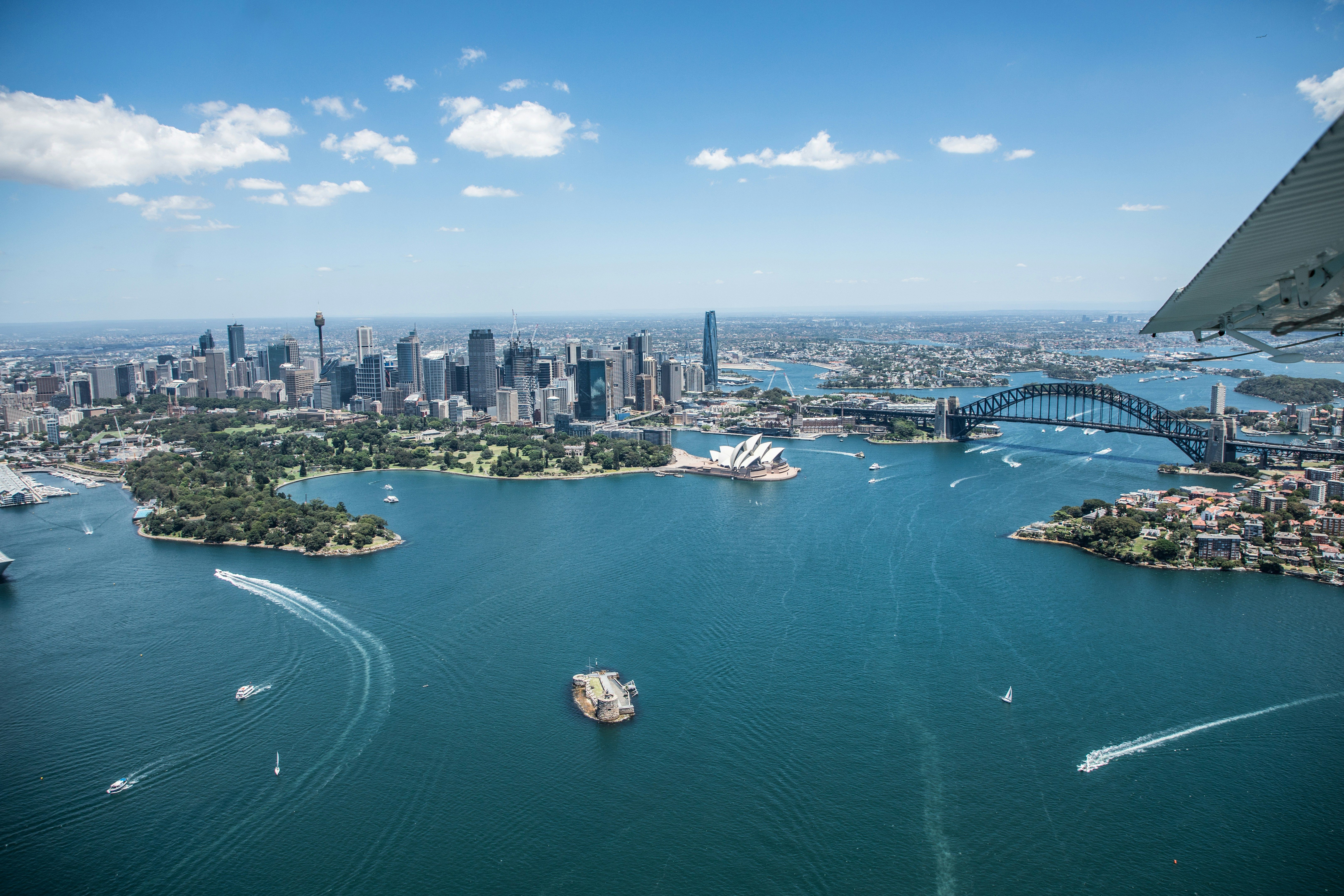 Voyage en Australie - Vue aérienne spectaculaire de la baie de Sydney avec l'Opéra et le Harbour Bridge sous un ciel azur Vue aérienne spectaculaire de la baie de Sydney avec l'Opéra et le Harbour Bridge sous un ciel azur